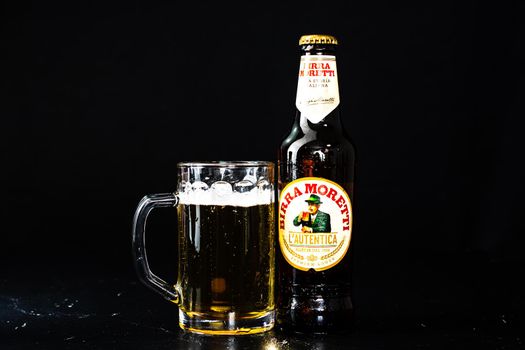 Can of Birra Morreti beer and beer glass on dark background. Illustrative editorial photo shot in Bucharest, Romania, 2021