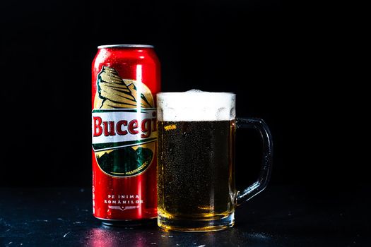 Can of Bucegi beer and beer glass on dark background. Illustrative editorial photo shot in Bucharest, Romania, 2021