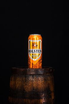 Can of Holsten beer on beer barrel with dark background. Illustrative editorial photo shot in Bucharest, Romania, 2021