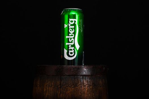 Can of Carsberg beer on beer barrel with dark background. Illustrative editorial photo shot in Bucharest, Romania, 2021