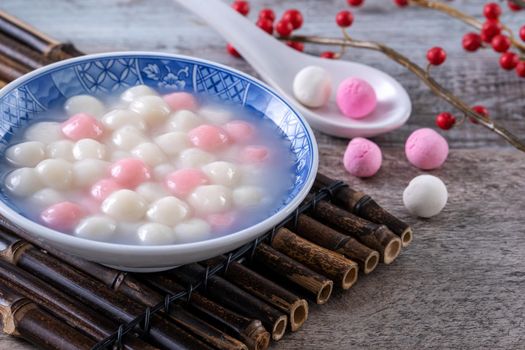Close up of red and white tangyuan (tang yuan, glutinous rice dumpling balls) in blue bowl on wooden background for Winter solstice festival food.