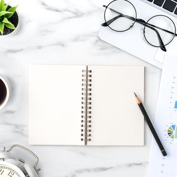 Top view of office table desk work concept with blank notebook, report, alarm clock on marble white background, concept of timing management and schedule planning.