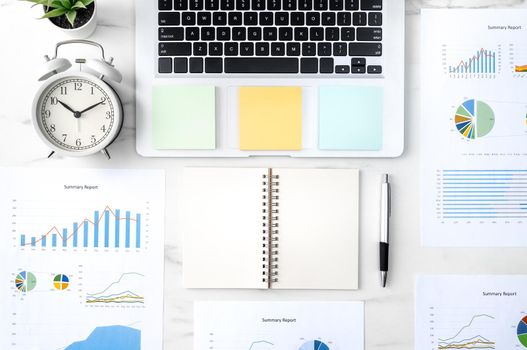 Top view of office table desk work concept with blank notebook, report, alarm clock on marble white background, concept of timing management and schedule planning.