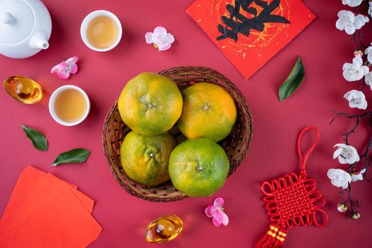 Top view of fresh ripe tangerine mandarin orange with fresh leaves on red table background for Chinese lunar new year fruit concept, the Chinese word means spring.