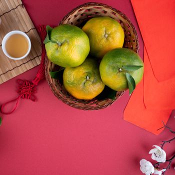 Top view of fresh ripe tangerine mandarin orange with fresh leaves on red table background for Chinese lunar new year fruit concept, the Chinese word means spring.