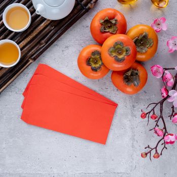 Top view of fresh sweet persimmons kaki with leaves on gray table background for Chinese lunar new year fruit design concept, the word means spring is coming.