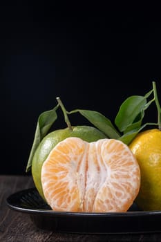 Fresh green tangerine mandarin orange with fresh leaves on dark wooden table background harvest concept.