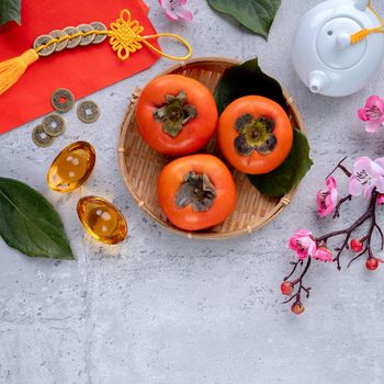Top view of fresh sweet persimmons kaki with leaves on gray table background for Chinese lunar new year fruit design concept, the word means spring is coming.