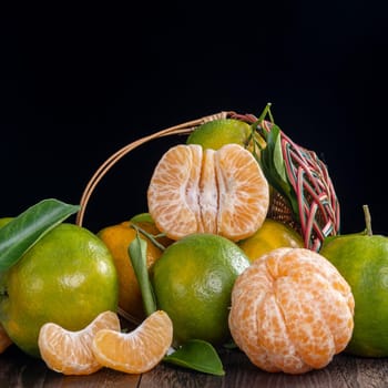 Fresh green tangerine mandarin orange with fresh leaves on dark wooden table background harvest concept.