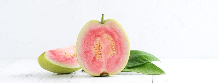 Close up of delicious beautiful Red guava with fresh green leaves isolated on white table background, studio table shot with copy space.