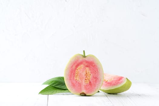 Close up of delicious beautiful Red guava with fresh green leaves isolated on white table background, studio table shot with copy space.