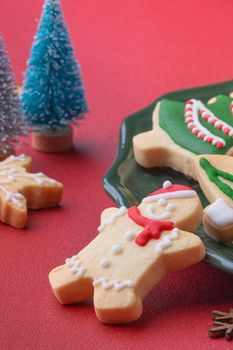Close up of Christmas decorated sugar cookies in a plate on red table background.