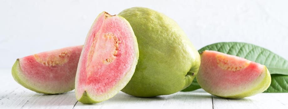 Close up of delicious beautiful Red guava with fresh green leaves isolated on white table background, studio table shot with copy space.