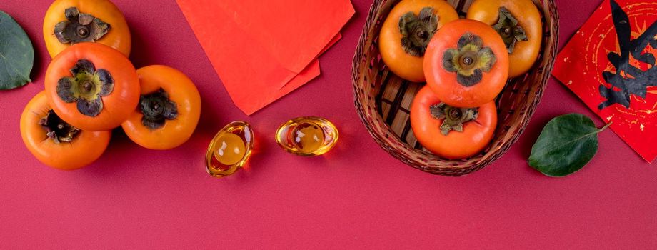 Top view of fresh sweet persimmons kaki with leaves on red table background for Chinese lunar new year fruit design concept, the word means spring is coming.