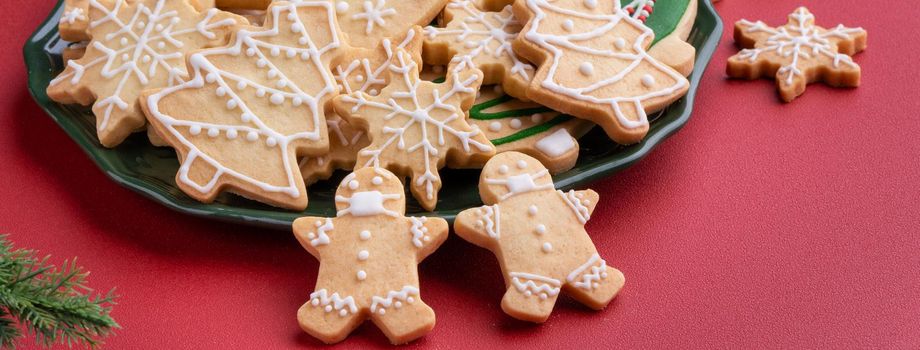 Close up of Christmas decorated sugar cookies in a plate on red table background.