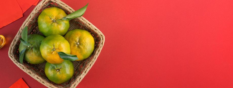 Top view of fresh ripe tangerine mandarin orange with fresh leaves on red table background for Chinese lunar new year fruit concept, the Chinese word means spring.