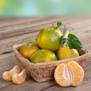 Fresh ripe tangerine mandarin orange in a box with fresh leaves on wooden table background harvest concept.