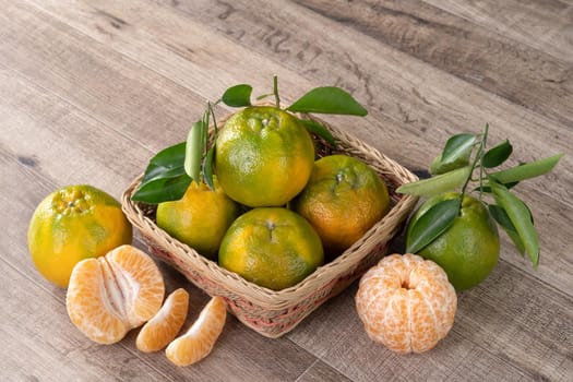 Fresh ripe tangerine mandarin orange in a box with fresh leaves on wooden table background harvest concept.
