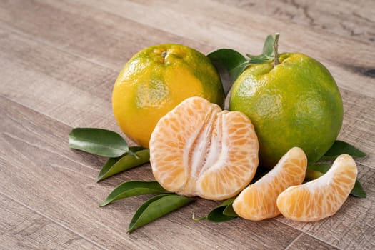 Fresh ripe tangerine mandarin orange in a box with fresh leaves on wooden table background harvest concept.