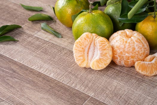 Fresh ripe tangerine mandarin orange in a box with fresh leaves on wooden table background harvest concept.