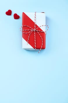 Valentine's Day greeting handmade gift design concept - Top view of wrapped gift box on bright blue background, flat lay overhead layout.