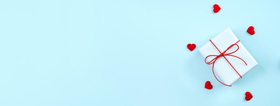 Valentine's Day greeting handmade gift design concept - Top view of wrapped gift box on bright blue background, flat lay overhead layout.