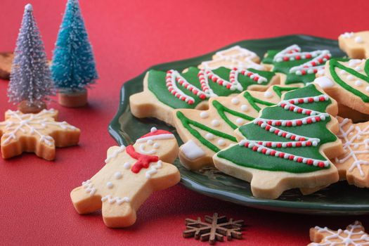 Close up of Christmas decorated sugar cooikes in a plate on red table background.