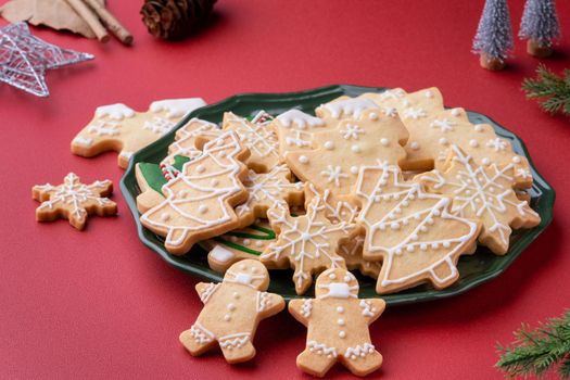 Close up of Christmas decorated sugar cooikes in a plate on red table background.