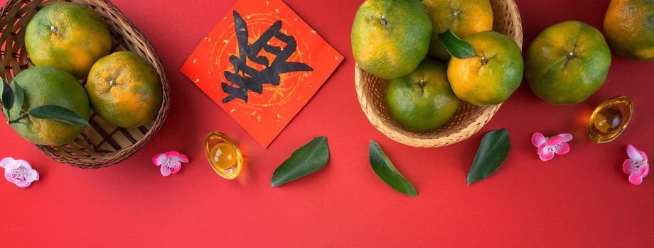 Top view of fresh ripe tangerine mandarin orange with fresh leaves on red table background for Chinese lunar new year fruit concept, the Chinese word means spring.