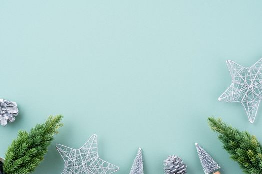 Top view of Christmas holiday decoration ornament composition with Christmas tree, gift star, gingerbread man flat lay with copy space isolated on green background.