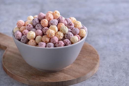 Colorful cereal corn balls mix, fruit flavor bowl sweets on gray cement background, close up, fresh, delicious and healthy breakfast, copy space design concept.