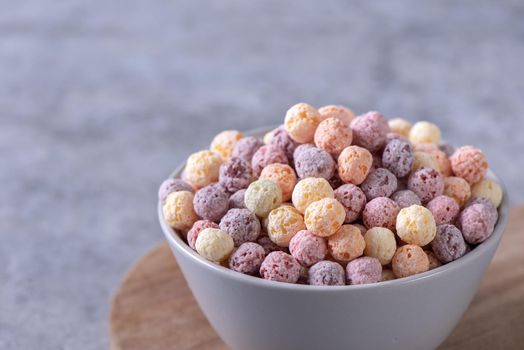 Colorful cereal corn balls mix, fruit flavor bowl sweets on gray cement background, close up, fresh, delicious and healthy breakfast, copy space design concept.