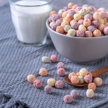 Colorful cereal corn balls mix, fruit flavor bowl sweets on gray cement background, close up, fresh, delicious and healthy breakfast, copy space design concept.