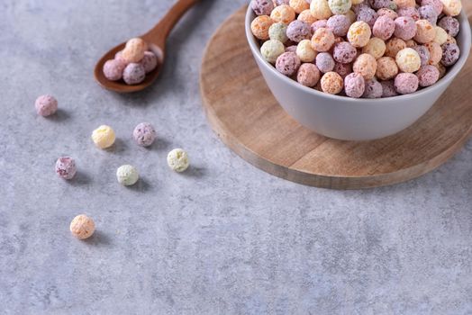 Colorful cereal corn balls mix, fruit flavor bowl sweets on gray cement background, close up, fresh, delicious and healthy breakfast, copy space design concept.