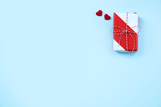 Valentine's Day greeting handmade gift design concept - Top view of wrapped gift box on bright blue background, flat lay overhead layout.