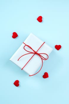 Valentine's Day greeting handmade gift design concept - Top view of wrapped gift box on bright blue background, flat lay overhead layout.