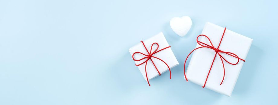 Valentine's Day greeting handmade gift design concept - Top view of wrapped gift box on bright blue background, flat lay overhead layout.