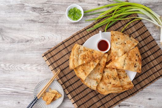 Taiwanese food - delicious flaky scallion pie pancakes on bright wooden table background, traditional snack in Taiwan, top view.