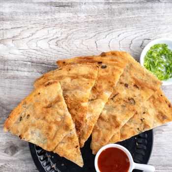 Taiwanese food - delicious flaky scallion pie pancakes on bright wooden table background, traditional snack in Taiwan, top view.
