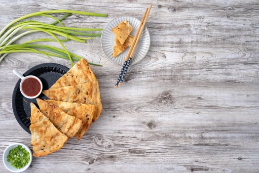 Taiwanese food - delicious flaky scallion pie pancakes on bright wooden table background, traditional snack in Taiwan, top view.