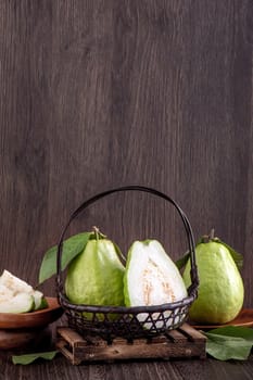 Close up of delicious beautiful guava set with fresh green leaves isolated on dark wooden table background.