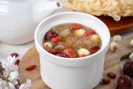 Close up of traditional Chinese sweet snow white fungus soup with lotus seed, red dates (jujube) and wolfberry (goji, gojiberry) on white background.