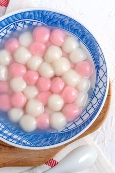 Top view of red and white tangyuan (tang yuan, glutinous rice dumpling balls) in blue bowl on white background for Winter solstice festival food.