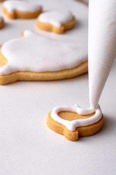 Close up of decorating cute Halloween gingerbread cookies with frosting icing cream topping bag.