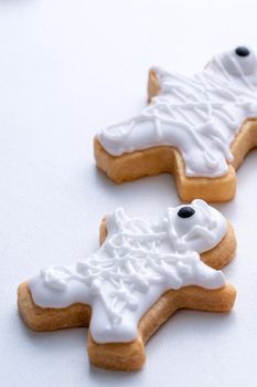 Close up of decorating cute Halloween gingerbread cookies with frosting icing cream topping bag.