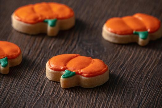 Close up of decorating cute Halloween pumpkin gingerbread cookies with frosting icing cream topping bag.