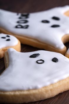 Close up of decorating cute Halloween ghost gingerbread cookies with frosting icing cream topping bag.