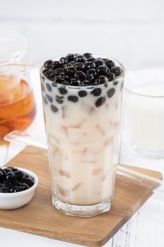 Bubble milk tea with tapioca pearl topping, famous Taiwanese drink on white wooden table background in drinking glass, close up, copy space