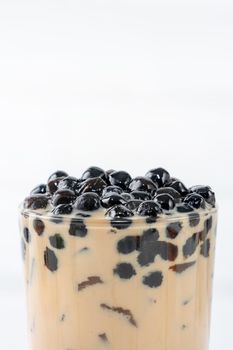 Bubble milk tea with tapioca pearl topping, famous Taiwanese drink on white wooden table background in drinking glass, close up, copy space