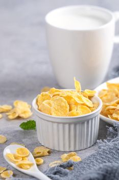 Corn flakes bowl sweeties with milk on gray cement background, close up, fresh and healthy breakfast design concept.